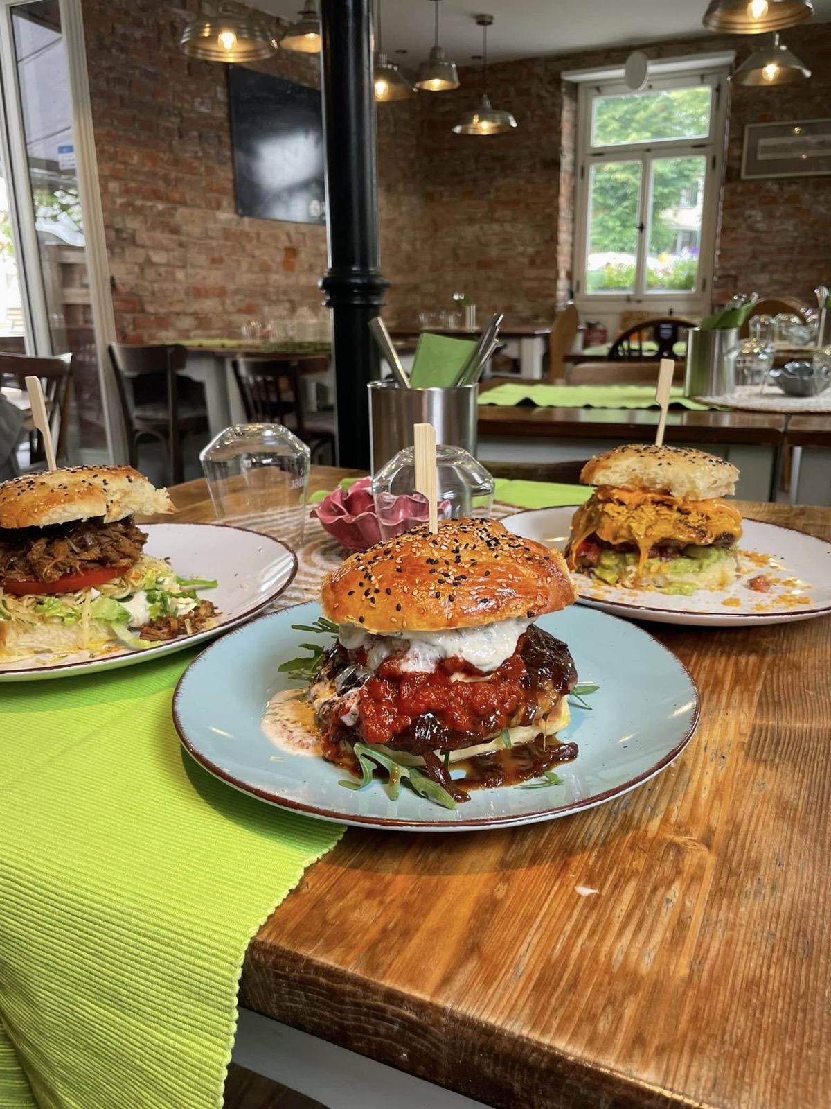 Drei Brioche-Burger auf Holztisch im Gastraum