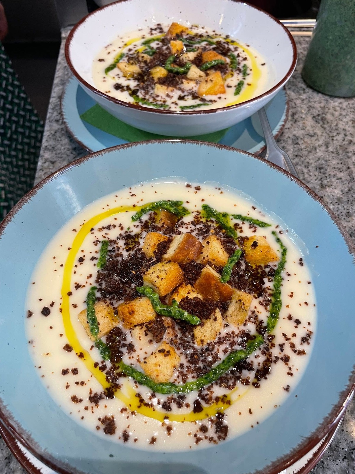 Cremesuppe mit Croutons, Pesto und Olivenöl in blauer Schale